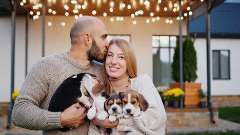 Retrato-De-Una-Feliz-Pareja-Joven-Con-Cachorros.-Parado-Frente-A-Su-Hermosa-Casa