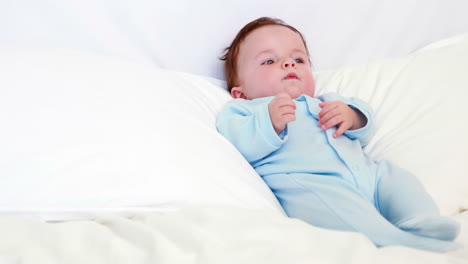 baby boy in blue babygro lying on pillows