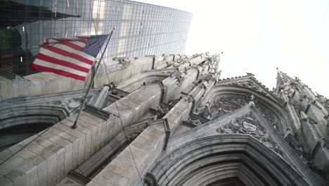 white and old church in the middle of manhattan with a dusty usa american flag waving.