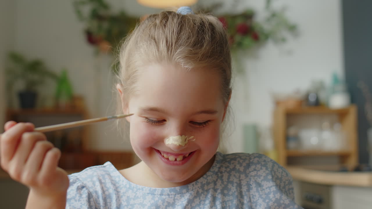 Bambina gioiosa che si mette la pittura sul naso