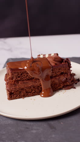 vertical video of person pouring melted chocolate sauce on slice of chocolate cake and eating it 1