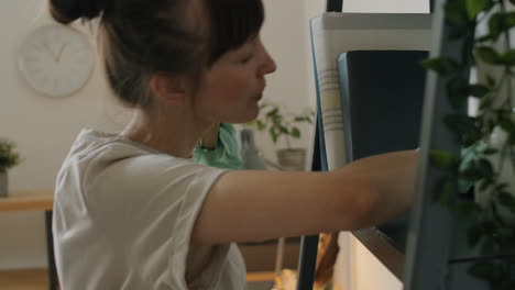 young woman cleaning bookshelf at home