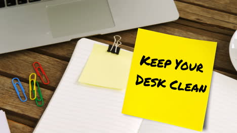 animation of keep your desk clean text on yellow memo note on desk with laptop, coffee and notebook