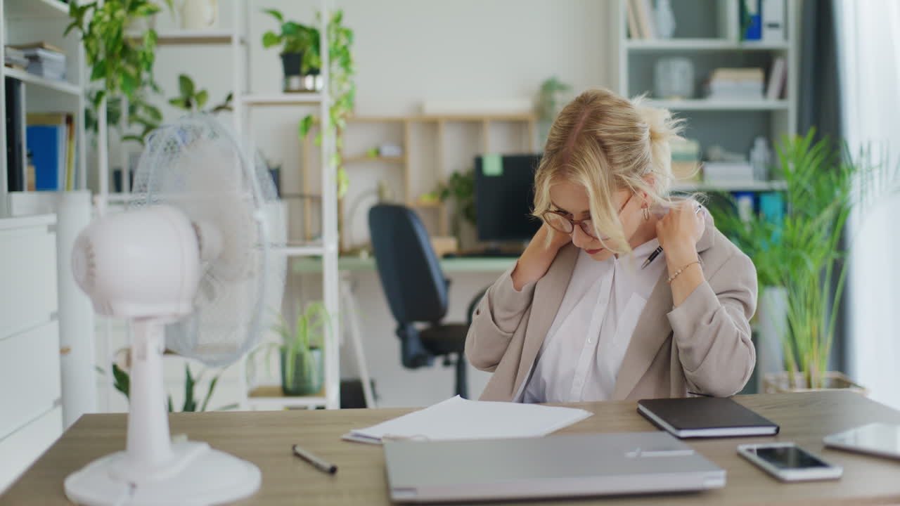 секретарь охлаждает себя вентилятором, чувствуя себя горячим.