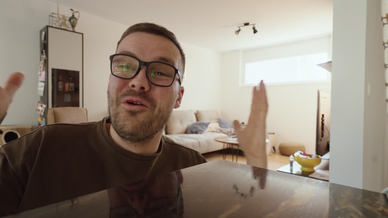Campo lungo di un uomo sorridente che reagisce con entusiasmo in un luminoso soggiorno, mostrando gioia, emozione positiva e uno stile di vita domestico autentico in un ambiente residenziale rilassato.
