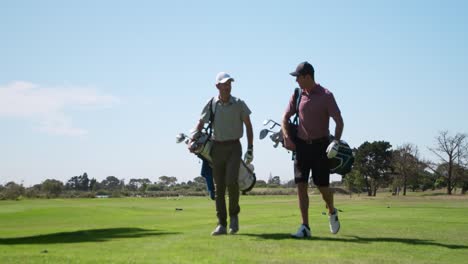 caucasian male golfers talking on a golf course on a sunny day