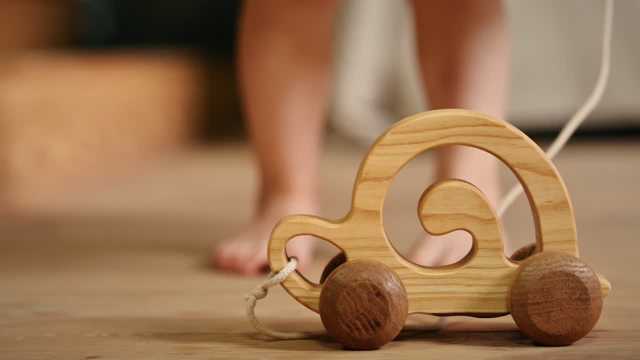 Little girl playing with a wooden snail rolling toy on the floor. Ecological and sustainability concept