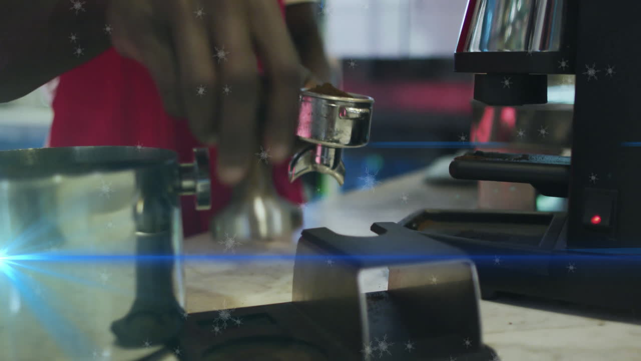 Male barista pressing tamper into portafilter on marble bar in cafe, featuring animated snowflakes