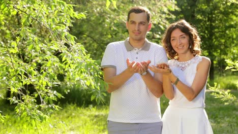 una pareja soplando diente de león en un parque