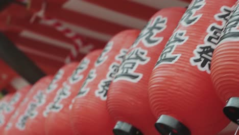 a close-up video capturing the intricate details of glowing red lanterns adorned with japanese writings at a temple, showcasing the spiritual ambiance and rich cultural heritage of the sacred site.