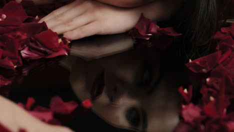 close up woman hand playing with red rose petals revealing reflection sensual female dreaming of intimate fantasy romance indulging desire in valentines day concept