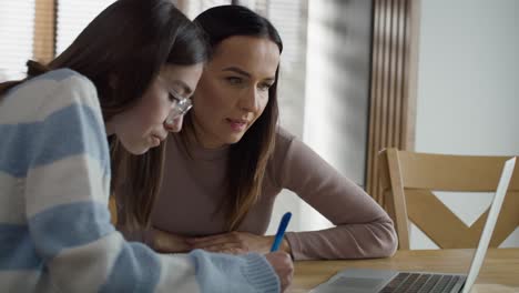 Madre-Caucásica-Ayudando-A-Su-Hija-Adolescente-A-Hacer-Los-Deberes-En-Casa