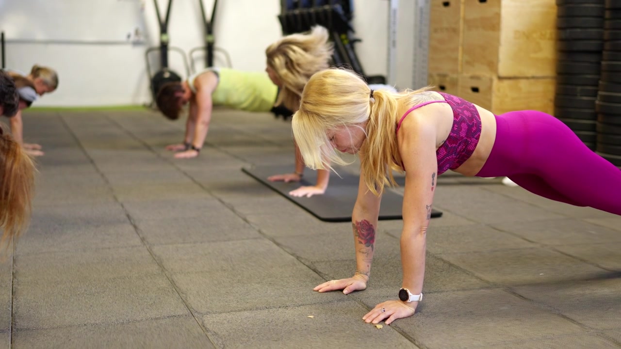 Gruppo di donne che eseguono l'esercizio del plank in una palestra.