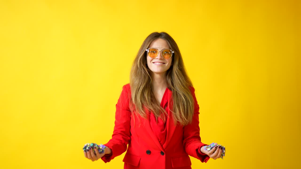 Woman celebrating with confetti on a yellow background