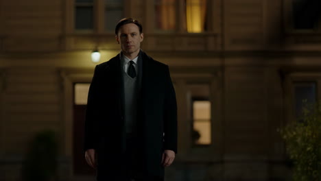 a man in a coat and tie standing outside at night