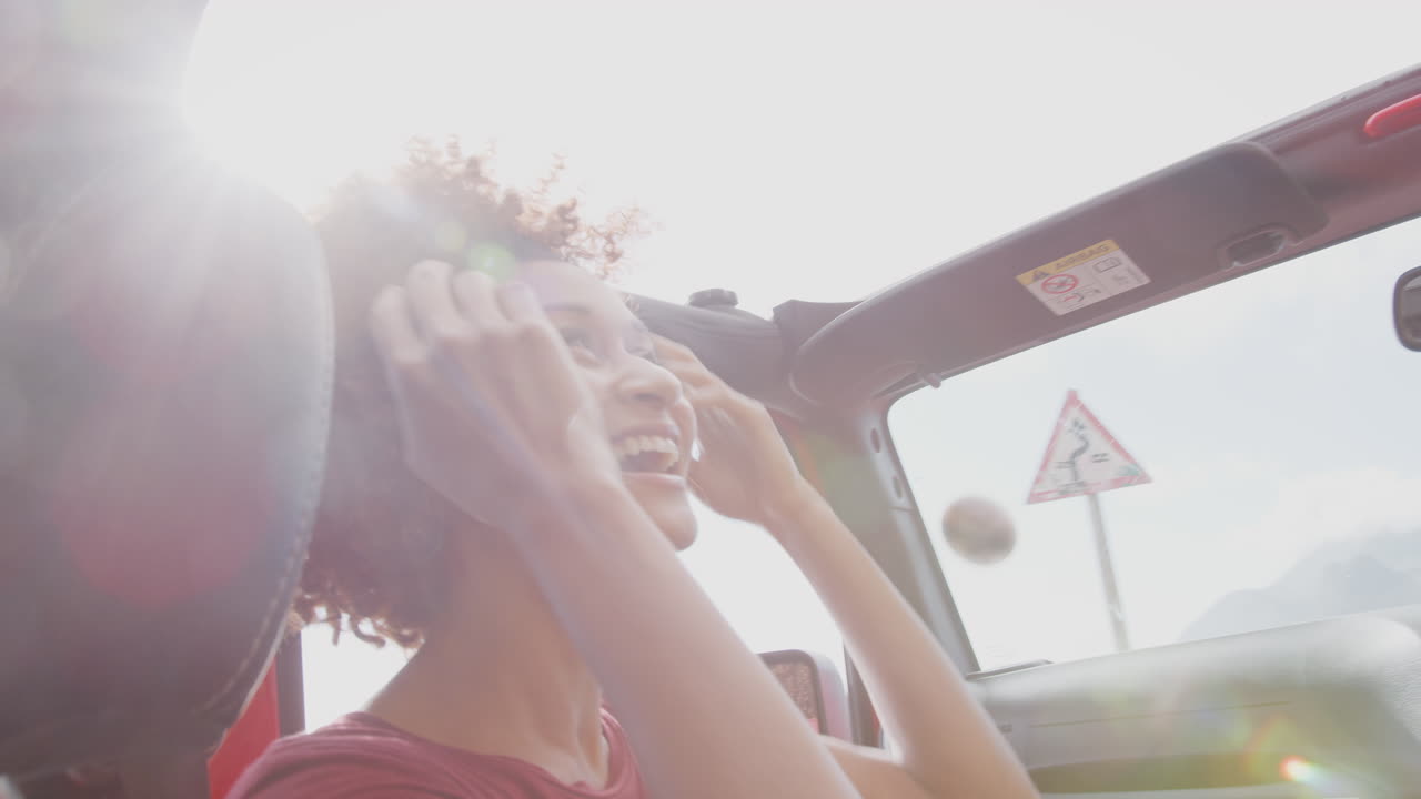 Young Female Passenger Having Fun In Open Top Hire Car On Summer Vacation