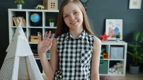 girl waving hello in her room