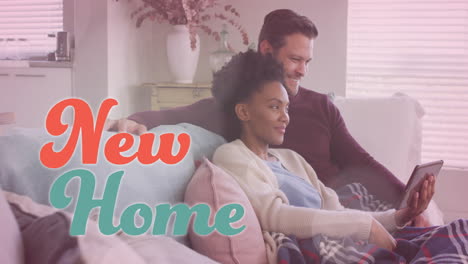 animation of new home text over diverse couple using tablet on sofa