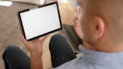 biracial man holding medication making video call using tablet, copy space on screen, slow motion