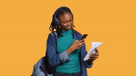 Student-listening-music-photographing-papers,-studio-background