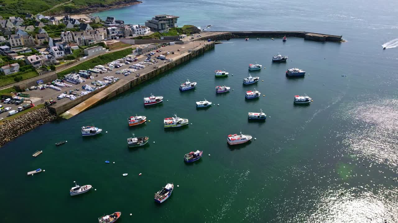 Backwards drone movement over the calm Vieux Port du Conquet marina with boats floating at harbor entrance, Le Conquet, Brittany, France.
