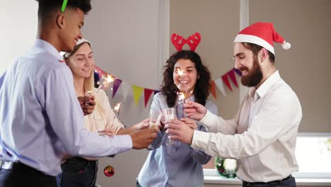 Group-of-young-people-toasting-for-achievements-in-New-Year-wearing-christmas-hats-and-deer-antler-headband-and-holding-Bengal