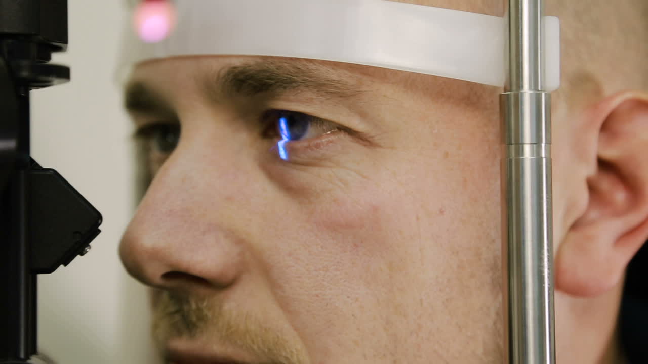 Man having eye test. Female optometrist examining mans eyes through slit lamp in clinic