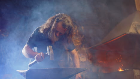 dramatic smokey shot of a blacksmith at work, hammering on anvil in the smithy