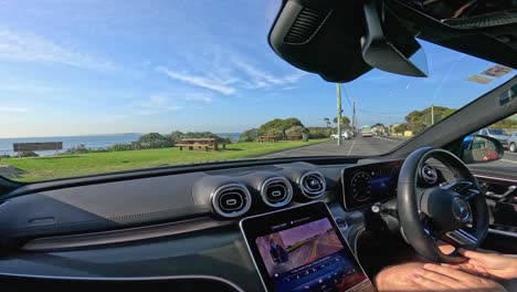 driver navigates coastal road in point lonsdale, capturing ocean views and residential scenery. bright daylight enhances the serene atmosphere