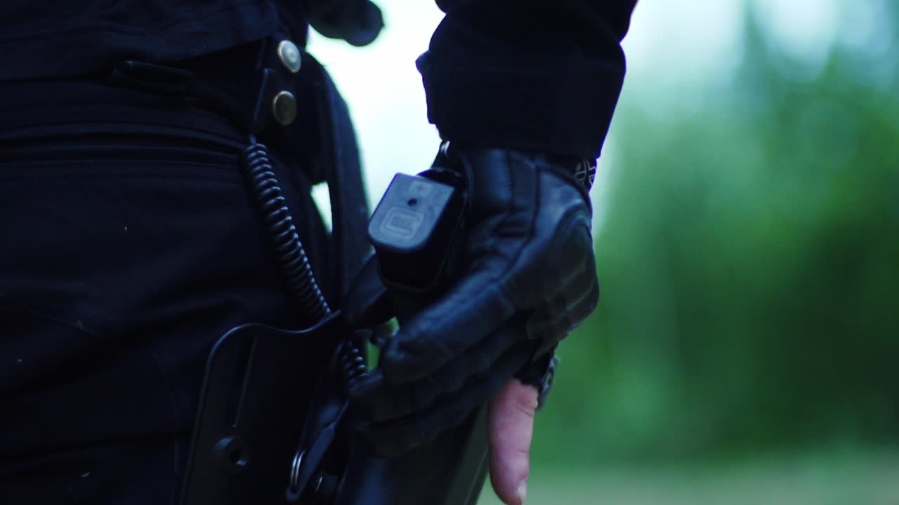Gloved operator fires pistol in slow motion with brass flying – tactical precision