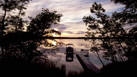 flying toward docked pontoon boat at sunset on reflective lake