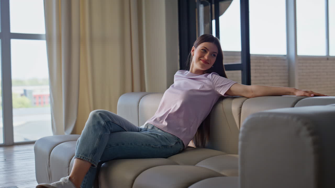 Carefree woman taking sit falling couch at home. Cheerful brunette girl rest