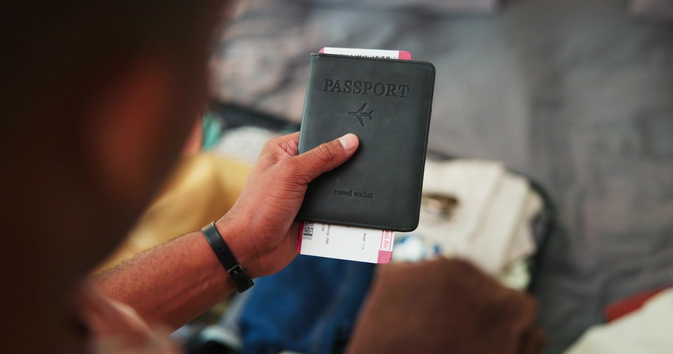 Person Holding Passport and Boarding Pass While Packing Suitcase