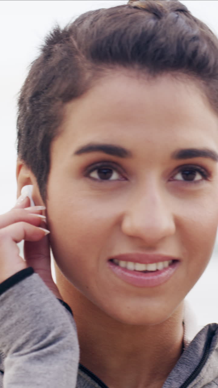 Primo piano di giovane donna che sistema l'auricolare wireless e sorride