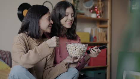 sisters watching a movie and eating popcorn