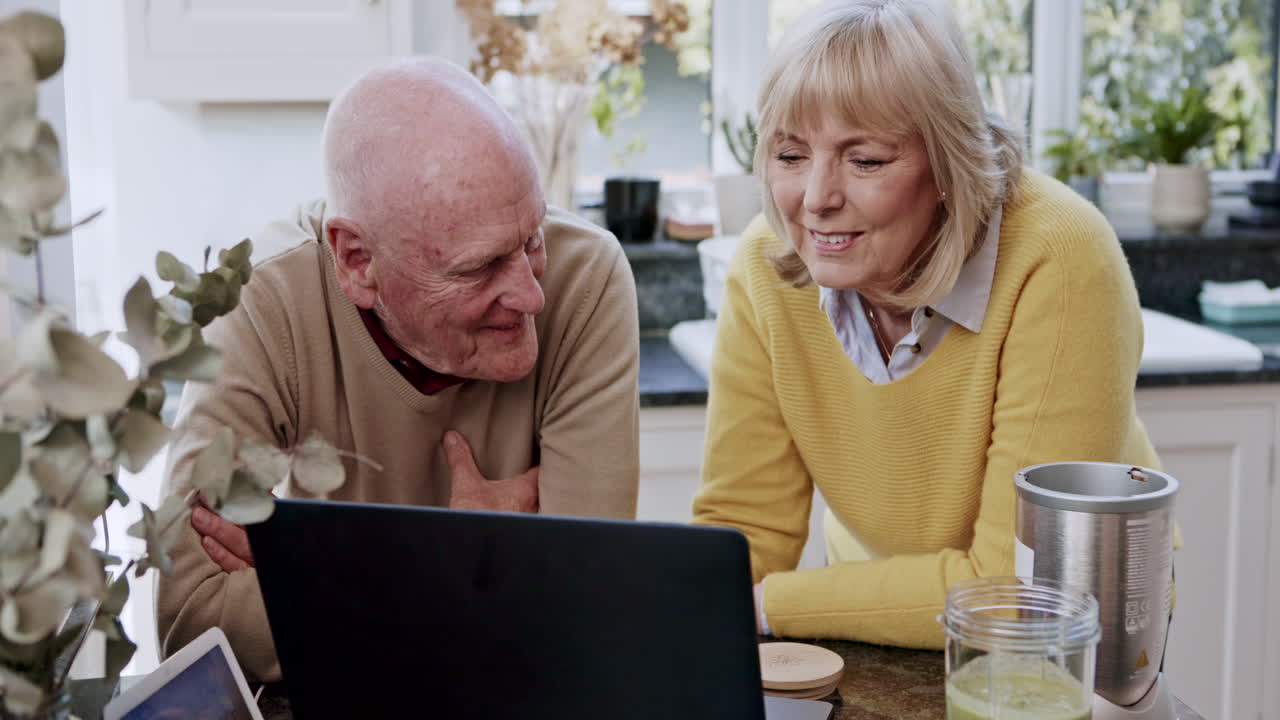 Senior couple using laptop in kitchen