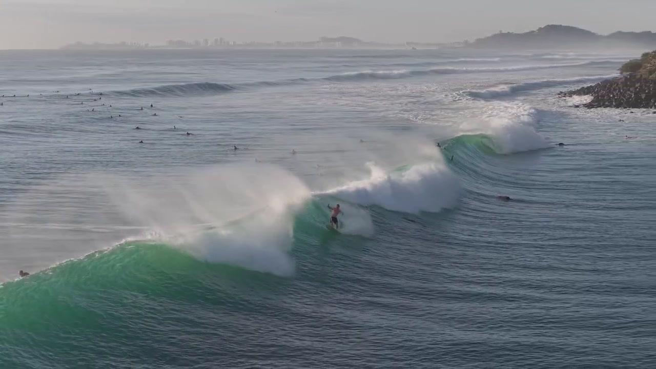Surffaaja nappaamassa täydellistä aaltoa aamusession aikana Gold Coastilla, Queenslandissa, Australiassa – ilmakuva.