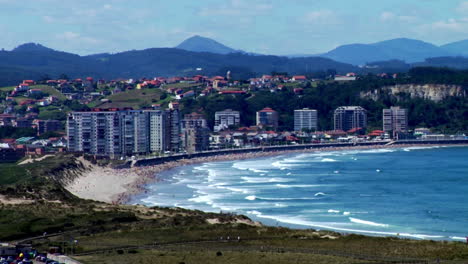 beachfront cityscape with waves and distant hills