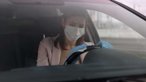mujer conduciendo un coche con máscara y guantes durante la pandemia