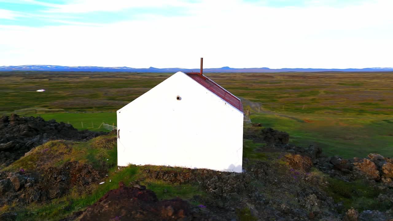 Fly over a unique house, sitting gracefully on aged lava, surrounded by the untouched beauty of Iceland.
