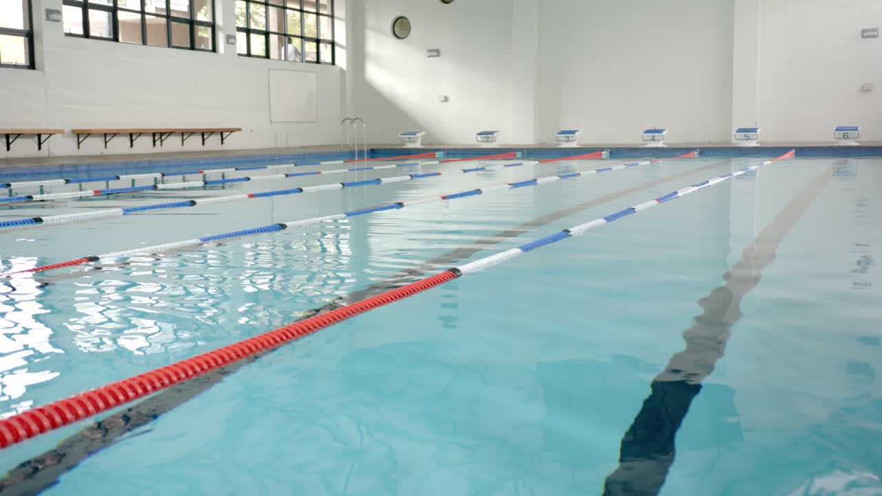 Empty indoor swimming pool with lane dividers, ready for swimmers to train, copy space