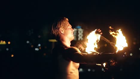 Young-blond-male-spins-two-burning-pois-tied-together-Slow-motion-shot-Close-up-shot