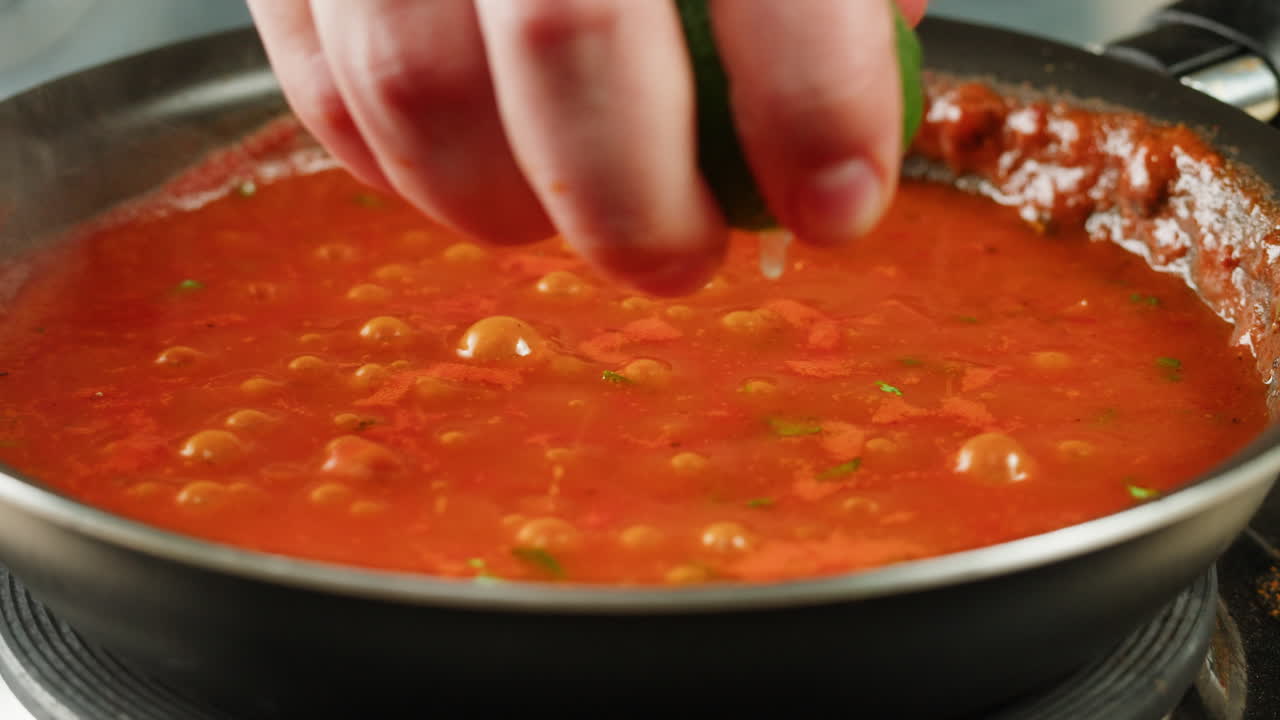 Chicken in tomato sauce is boiling on a frying pan with spices. Cooking tomato sauce curry with chicken fillet. Traditional Italian Mexican Asian dish. High quality studio shot for cafe, restaurant close up.