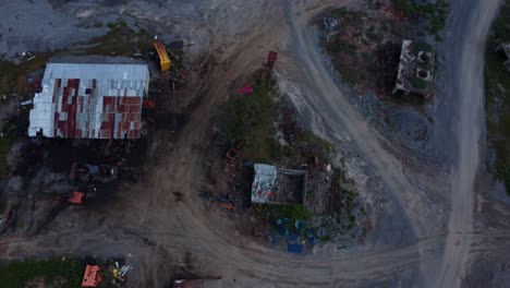 stunning view of an industrial scrapyard at twilight, highlighting rusted machinery and dirt roads with a moody, gritty atmosphere. overhead perspective reveals detailed textures, abuja, nigeria