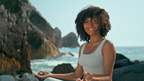 Frau-Schaut-In-Die-Kamera,-Sitzt-Im-Lotussitz-Am-Ursa-Beach,-Nahaufnahme.-Mädchenmeditation.