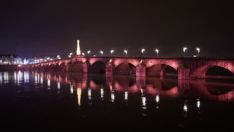 vista panorámica del puente jacques-gabriel en blois, francia con luces de la calle y vehículos que pasan por la noche.