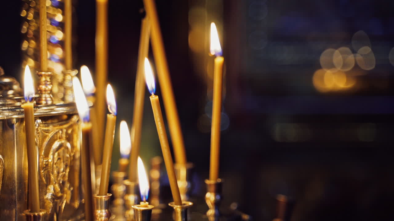 Bright wax candles burning in church. Abstract candles background. Golden light of candle flame. Candles light.