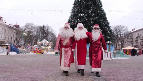 a group of santa clauses walk in the center of the city behind them the main christmas tree christmas time a group of santa clauses walk in the center of the city behind them the main christmas tree the concept of the new 2023 and christmas