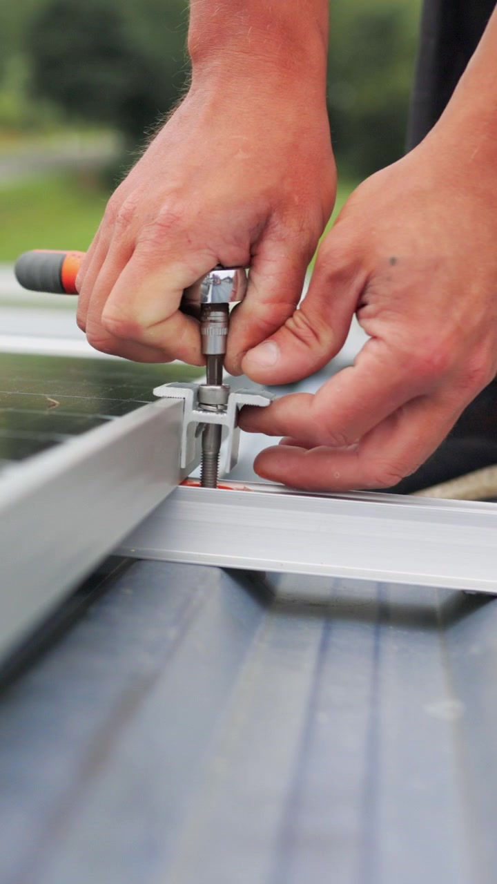 A closeup shot of a person installing a solar panel using a wrench to tighten a bolt showcasing the