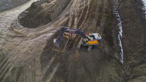 a large excavator loads dirt into a heavy haul dump truck at a construction site